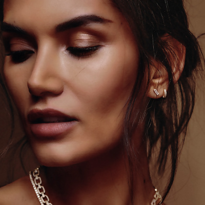 Model wearing Layered Geo - Mini Baguette Huggie Earrings in gold, other earrings and necklace