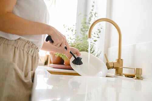 Washing dishes at a sink 