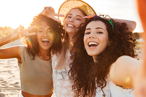 Three women smiling and taking a selfie at the beach