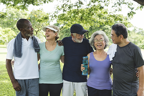 Group of elder friends laughing and smiling on a walk outside.